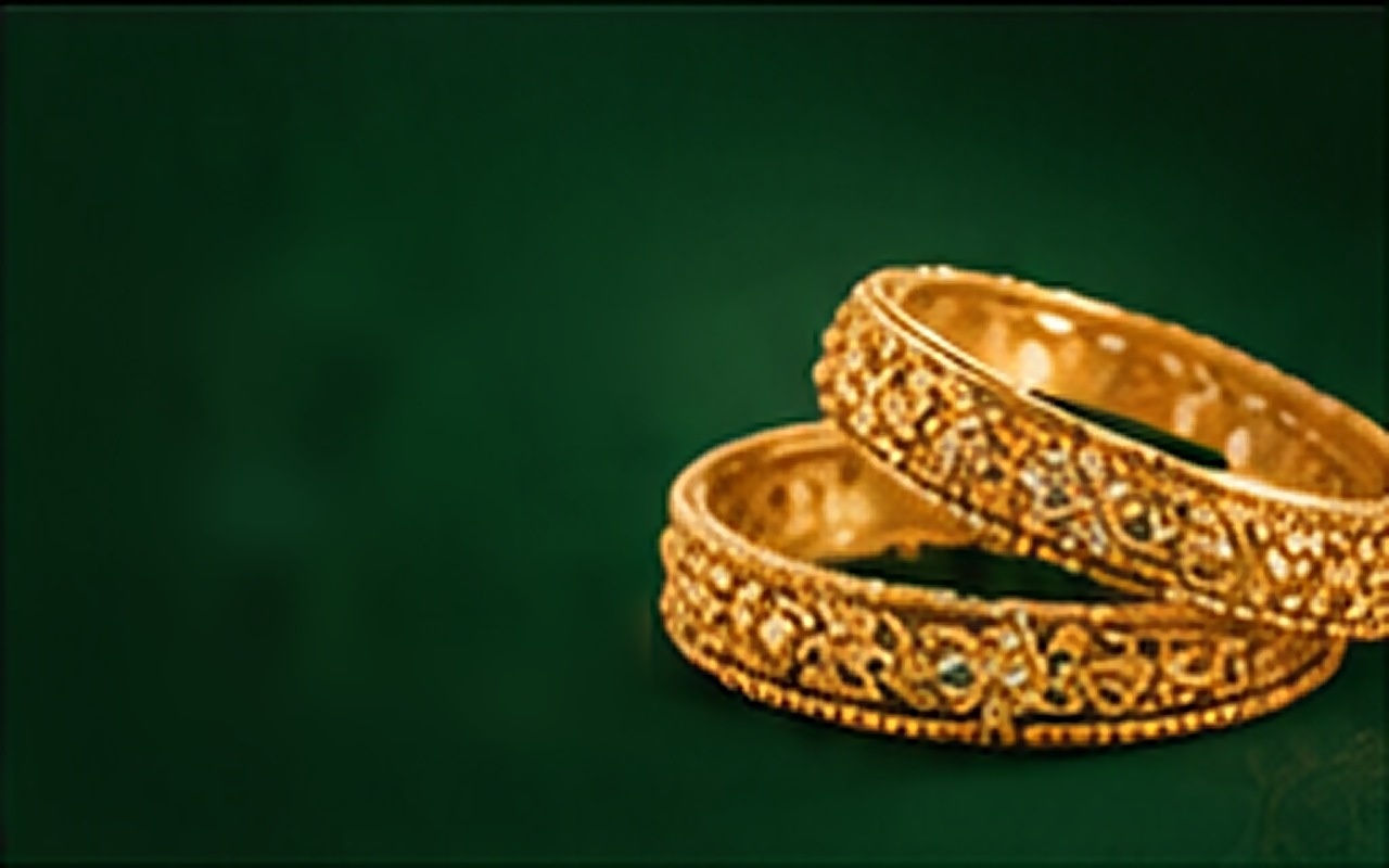 Pair of carved gold bangles on green velvet
